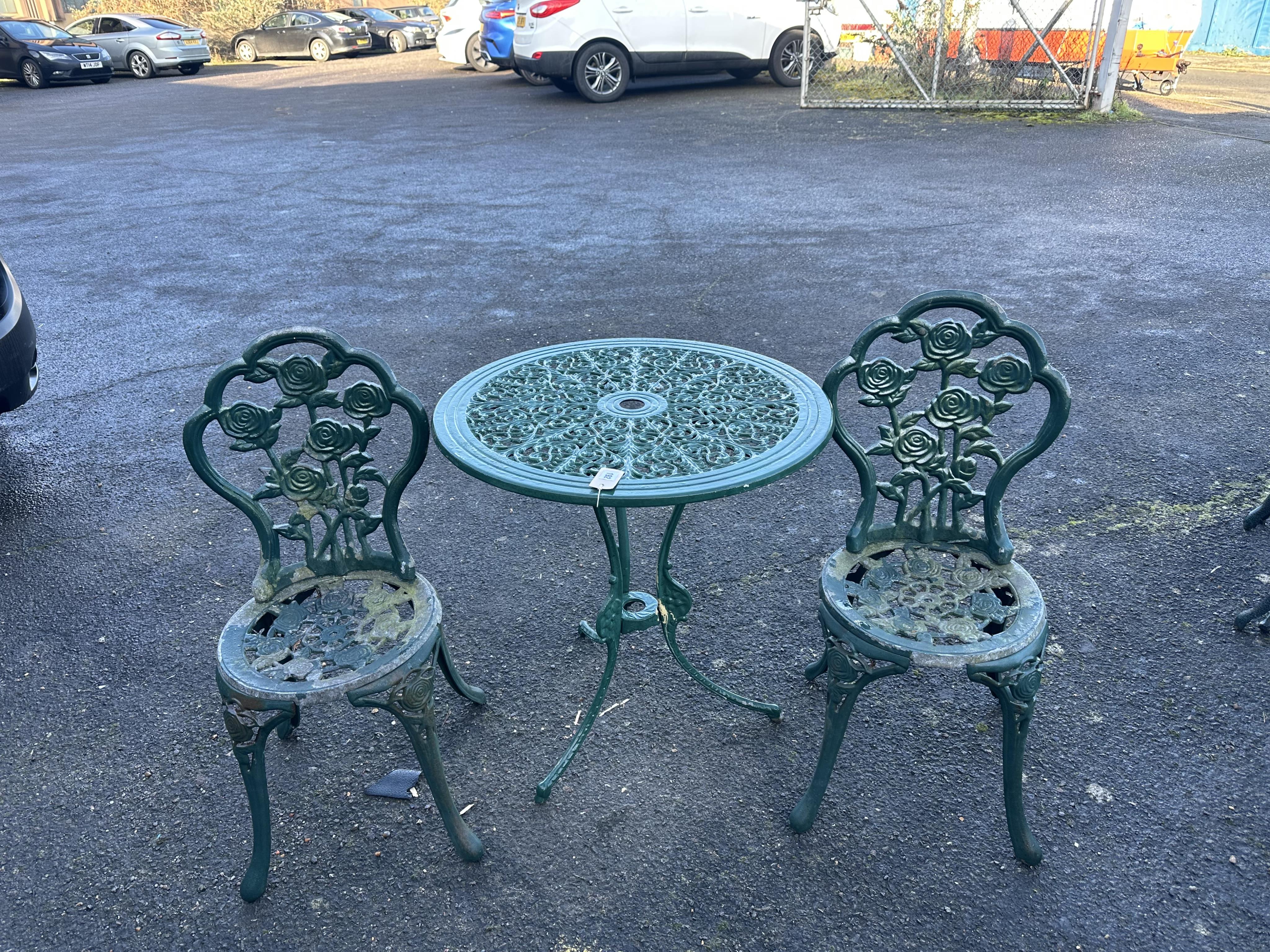 An aluminium garden table, diameter 68cm and a pair of chairs. Condition - poor